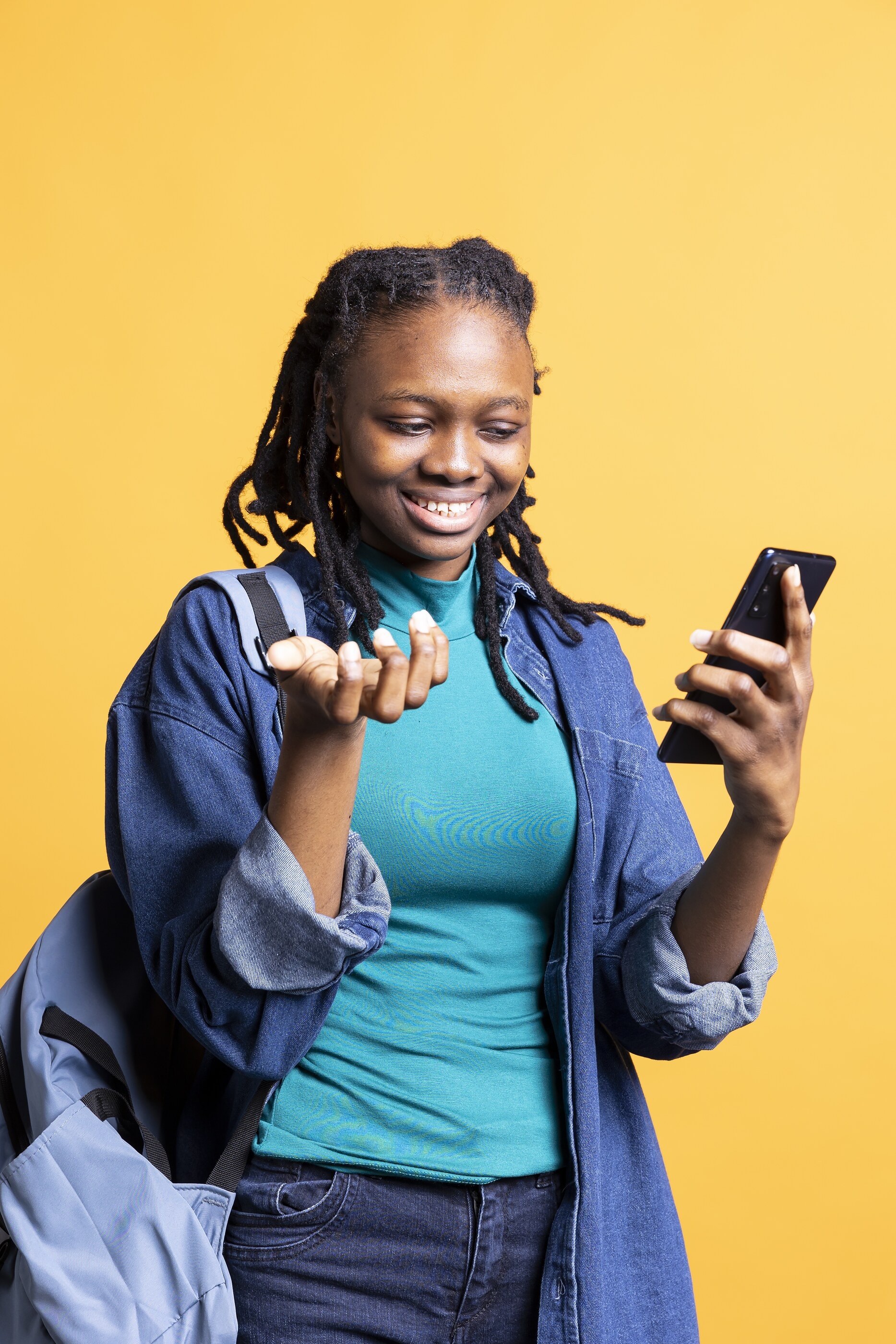 A young woman laughing as she reads a message on her phone
